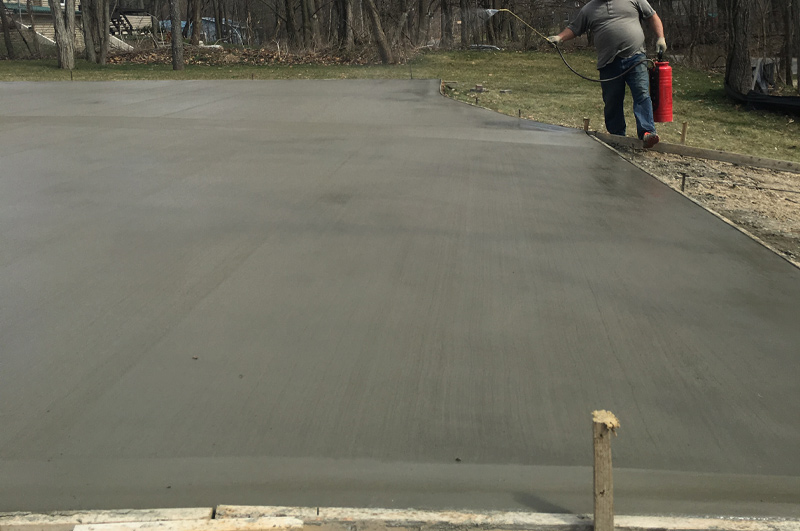 Curbed concrete driveway being sealed for winter protection in Millersburg, Indiana
