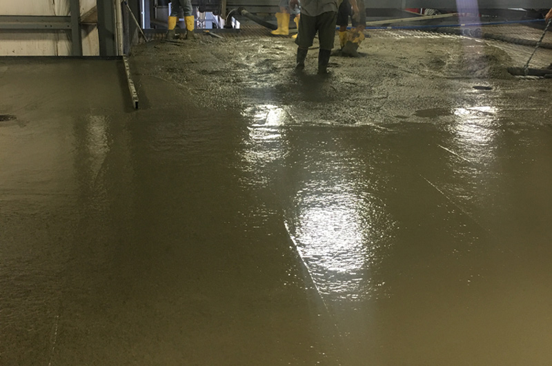 Crew coordinating concrete pump placement across the second-story floor at Lennard Ag